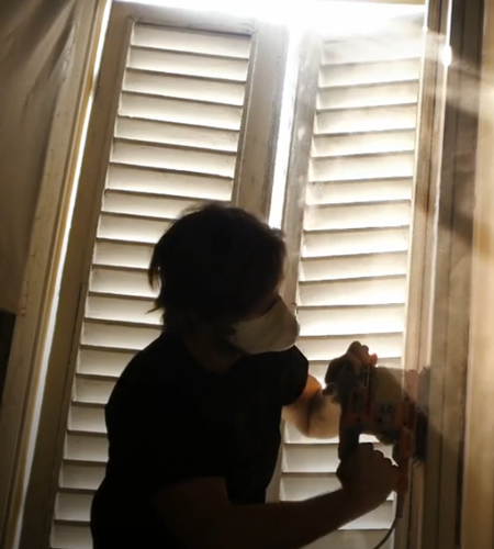 a worker sanding a shutter