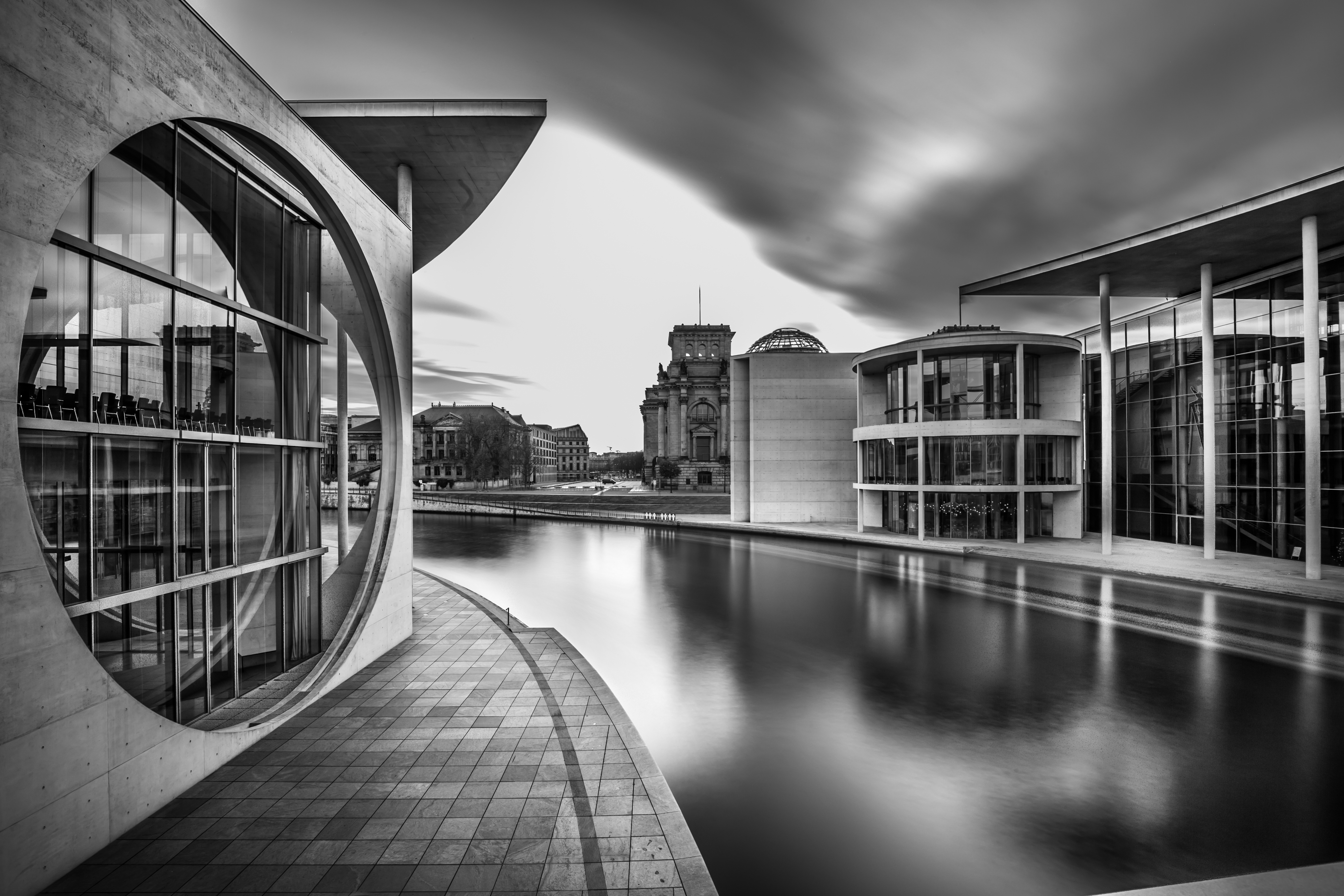 grayscale shot lake middle city buildings cloudy sky