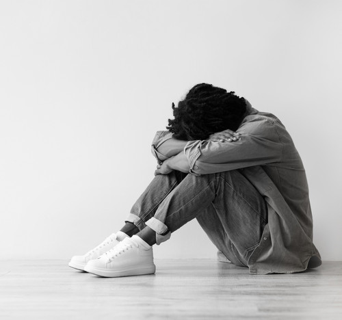 Smiling, unhappy, tired millennial black guy suffer from depression, stress sit on floor, make thumb.jpg