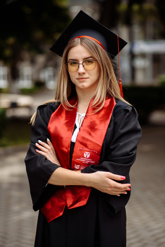 woman red black graduation gown is standing brick walkway.jpg