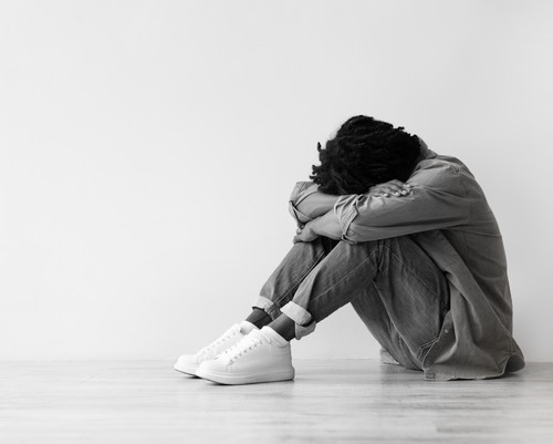 Smiling, unhappy, tired millennial black guy suffer from depression, stress sit on floor, make thumb.jpg