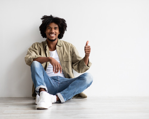 Smiling, unhappy, tired millennial black guy suffer from depression, stress sit on floor, make thumb.jpg