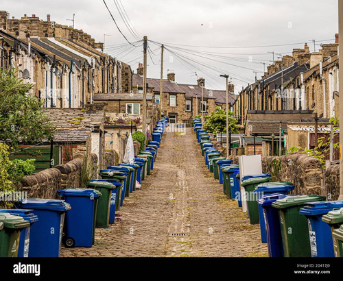 sloping cobbled back alley at rear of victorian terraced houses in skipton uk with lines of wheelie .jpg