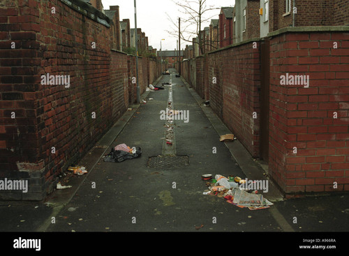 rubbish strewn about in a back alley of terraced houses moss side A966RA.jpg