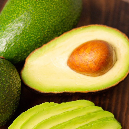 Avocado slices next to cutted one on a wooden board..jpg