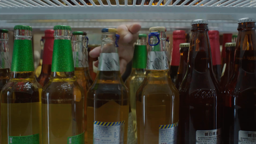 A hand reaching out to a group of bottlesDescription automatically generated