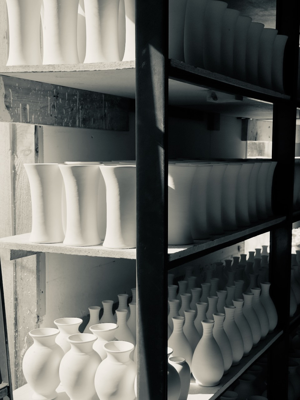 Shelves of white pottery waiting in the dark