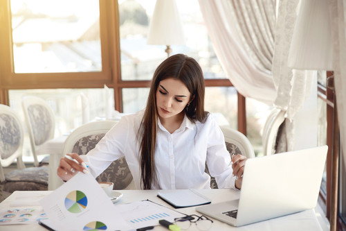 Young brunette business lady is analyzing diagrammes and working on the laptop.jpg