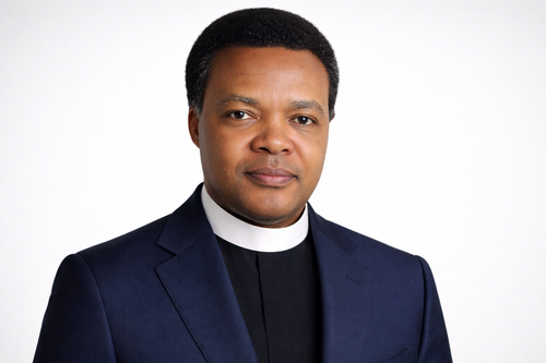 Confident clergyman in navy suit.png