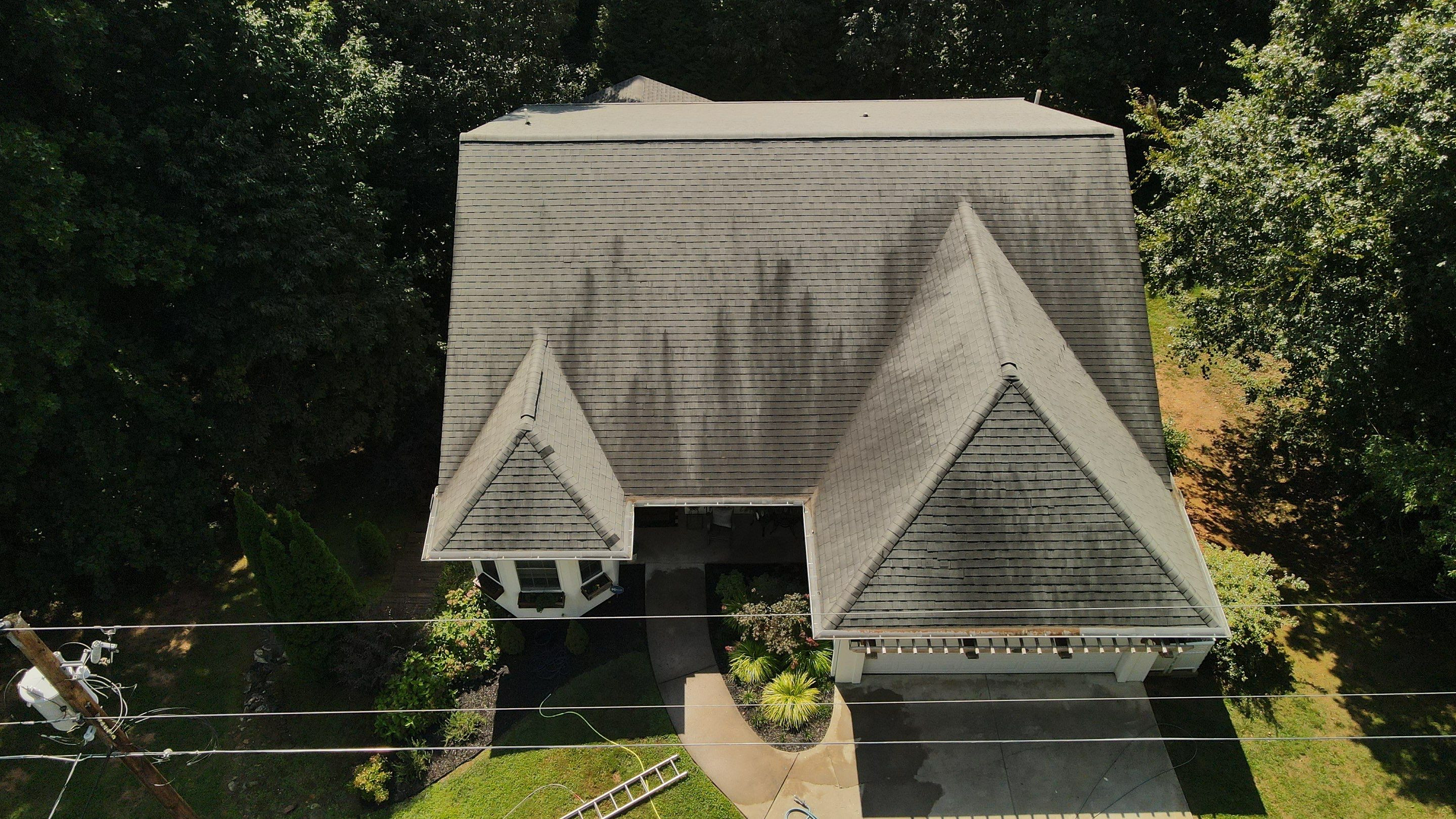 Roof covered in dark algae streaks before soft wash treatment