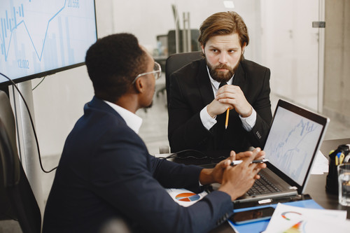 African man in a black suit. International partners. People sitting at the table with laptop..jpg