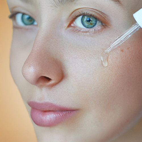 li woman applying facial serum dropper skincare routine.jpg