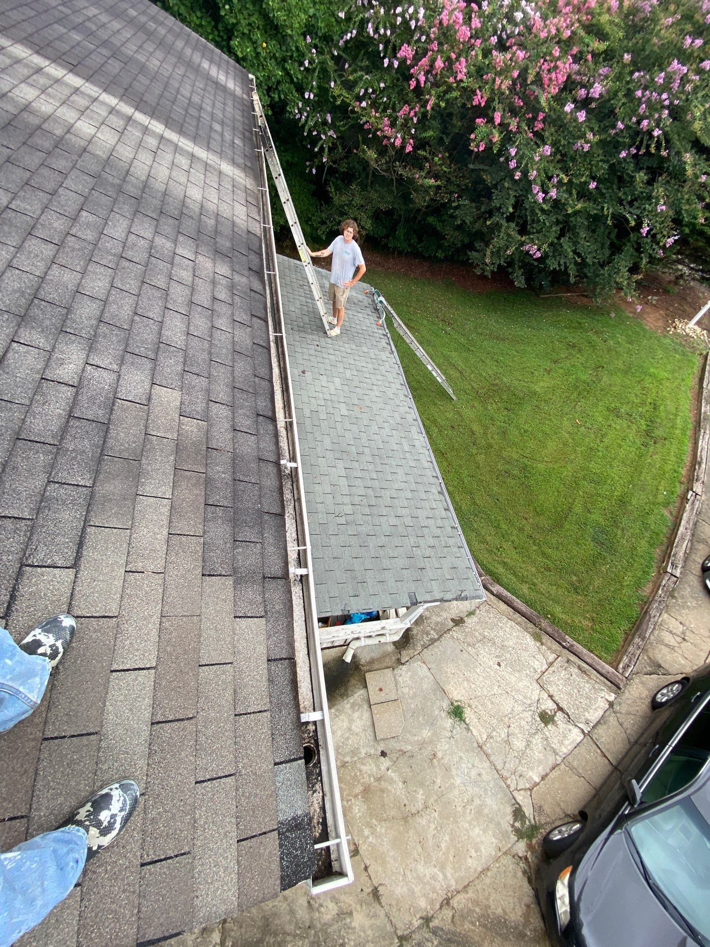 Professional gutter cleaning crew on roof removing debris from gutters on a home in North Georgia