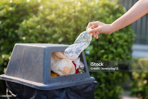 person is throwing away a plastic bottle in a trash can.jpg
