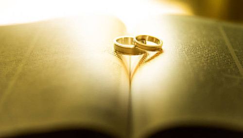 Two wedding rings with heart shadow  on a bible page.jpg