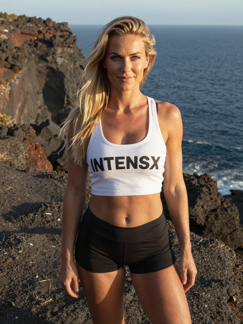 junge deutsche blondine steht auf vulkanfelsen am meer im sonnenlicht weisses intensx crop top.png