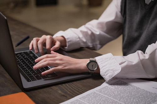 primer plano oficinista sentado su lugar trabajo escribiendo documentos computadora portatil oficina.jpg
