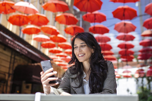 smiling woman drinking coffee using her mobile phone satisfied female enjoying cup coffee close up p.jpg