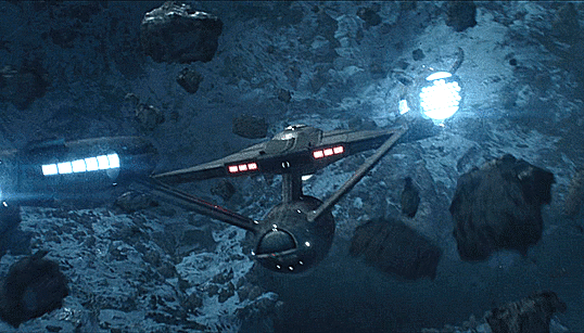 a gif of the USS Enterprise moving through an asteroid field