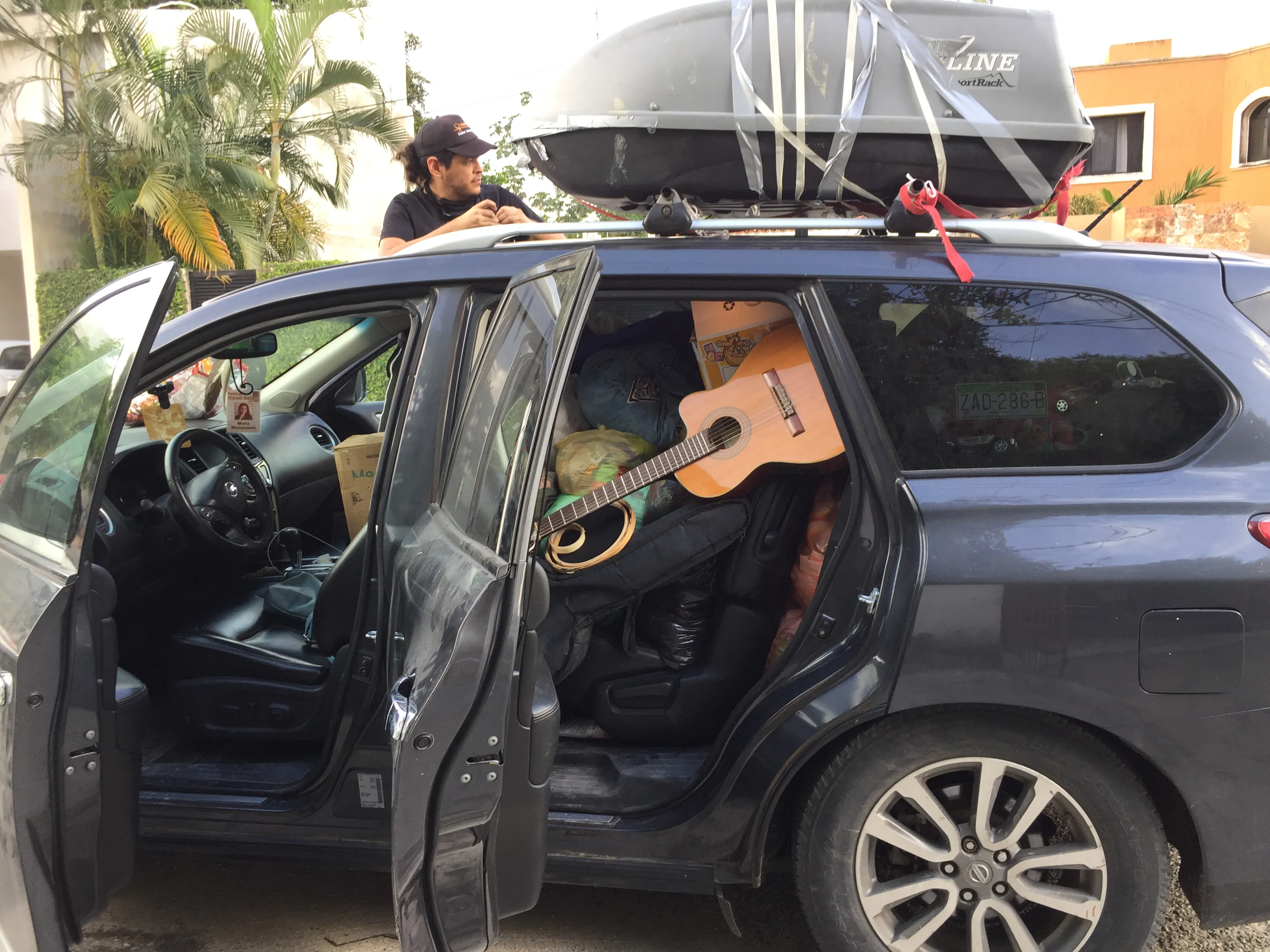 Daniel ajustando el maletero en el techo de una SUV llena de cosas