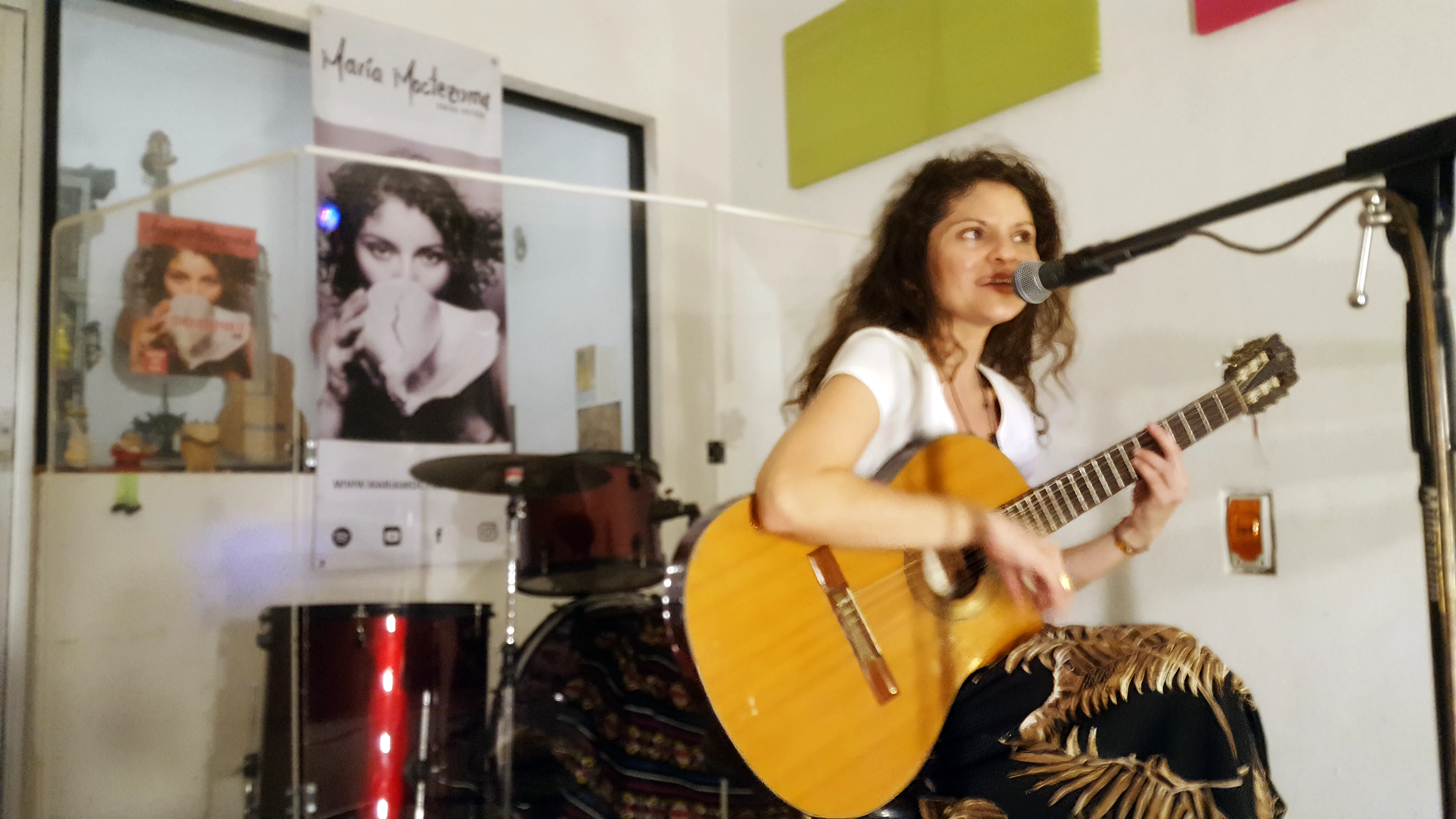 Maria Moctezuma sentada tocando la guitarra en transmisión en vivo desde su estudio