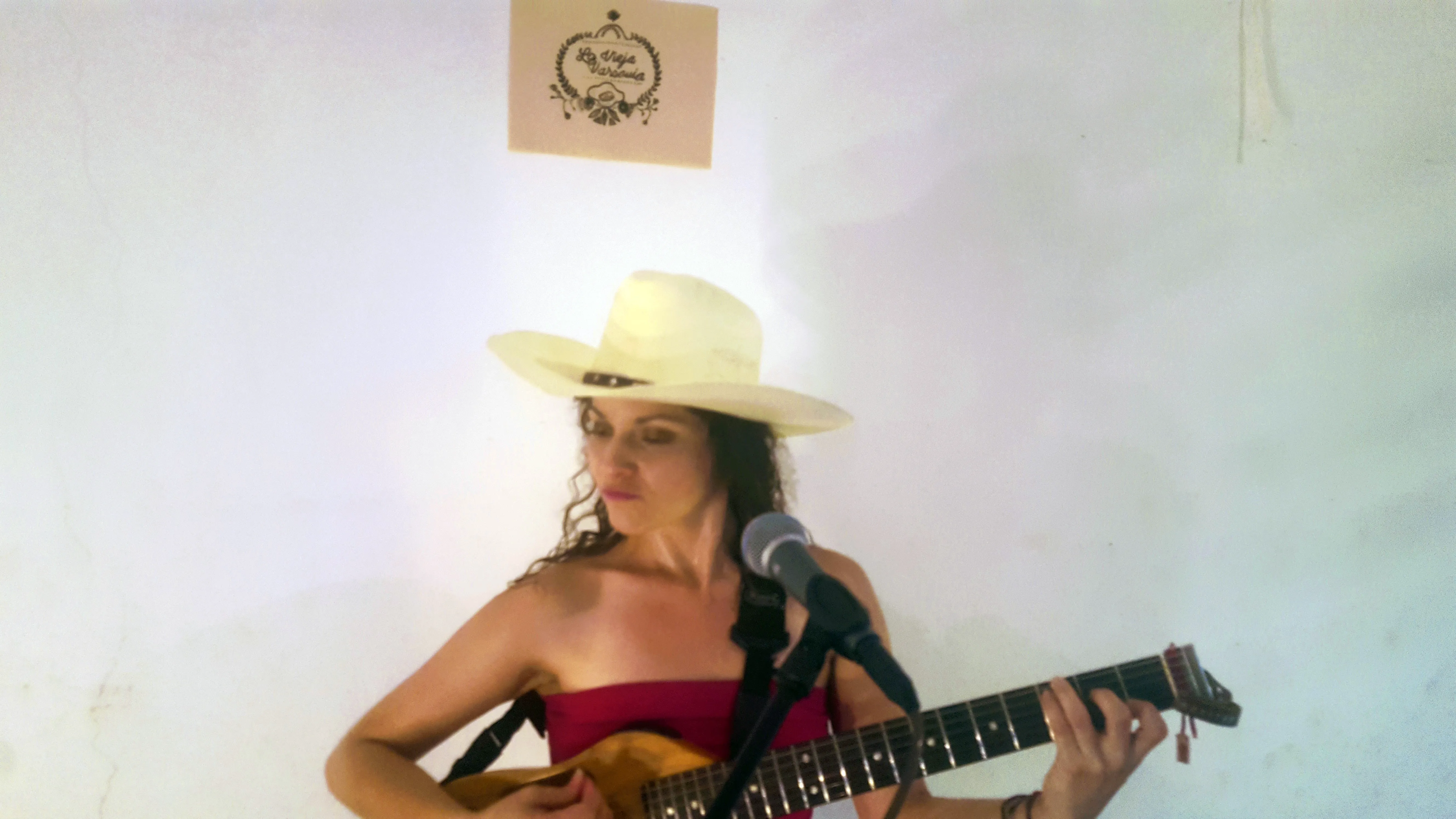 Maria Moctezuma con sombrero y guitarra frente al micrófono interpretando ❝Cómo animal a su presa❞