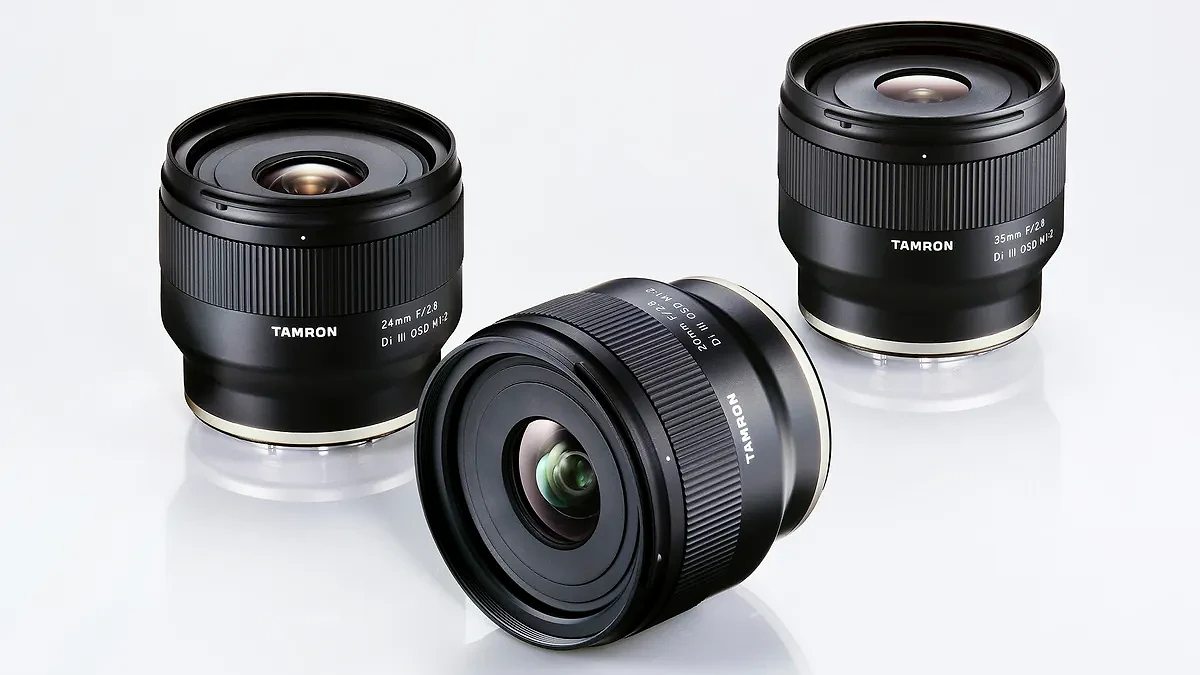 Three black Tamron camera lenses with white and gold accents on a white reflective surface