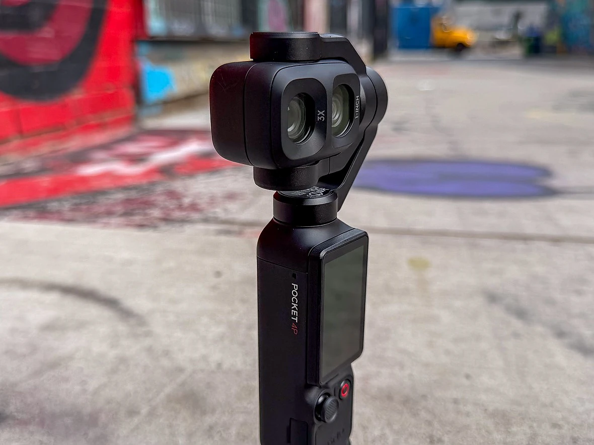 a dji gimabal camera sits on a sidewalk withgraffiti behind it