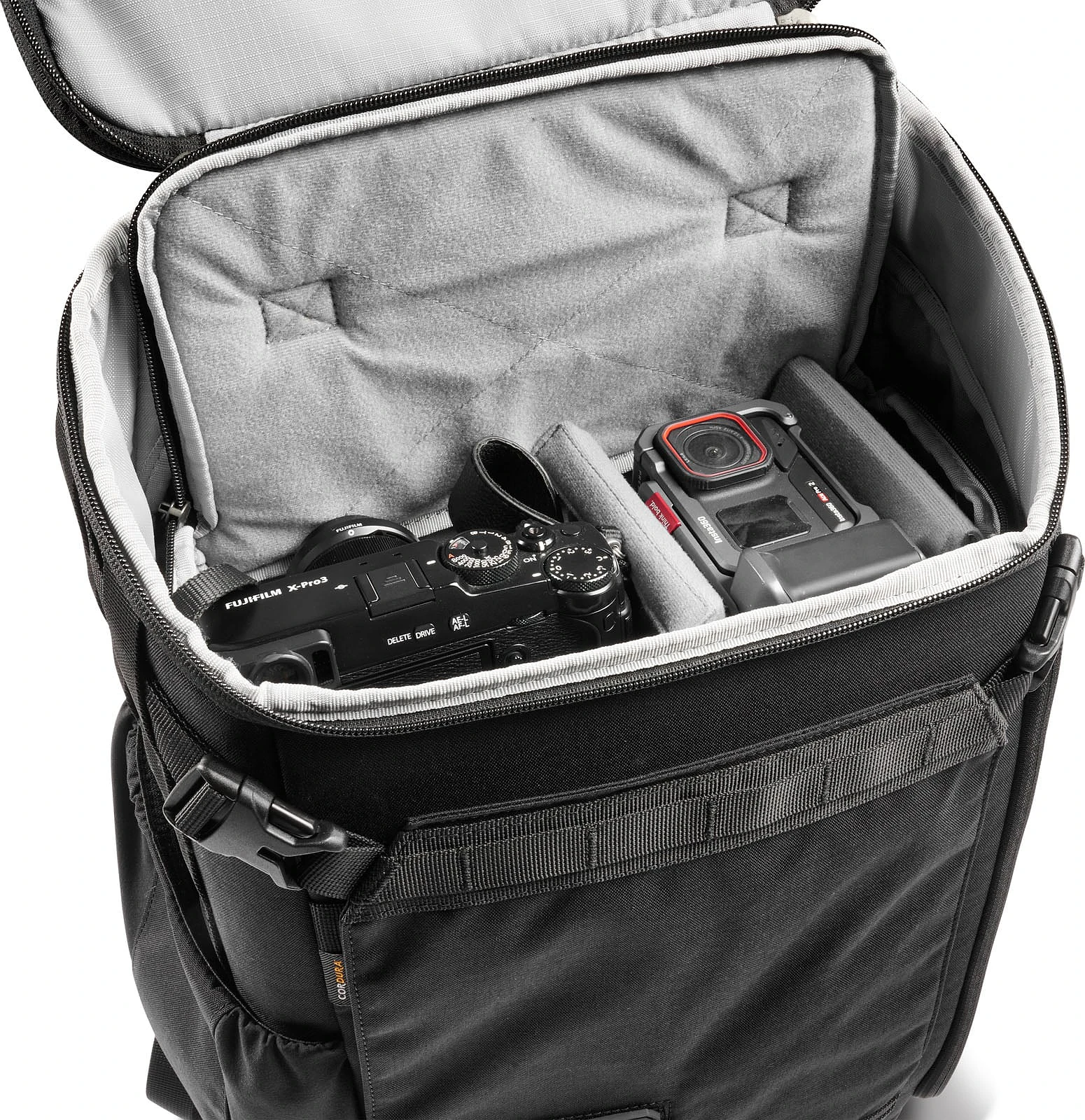 An open black camera backpack containing a Fujifilm X-Pro3 camera and an Insta360 Ace Pro 2 action camera separated by padded dividers.