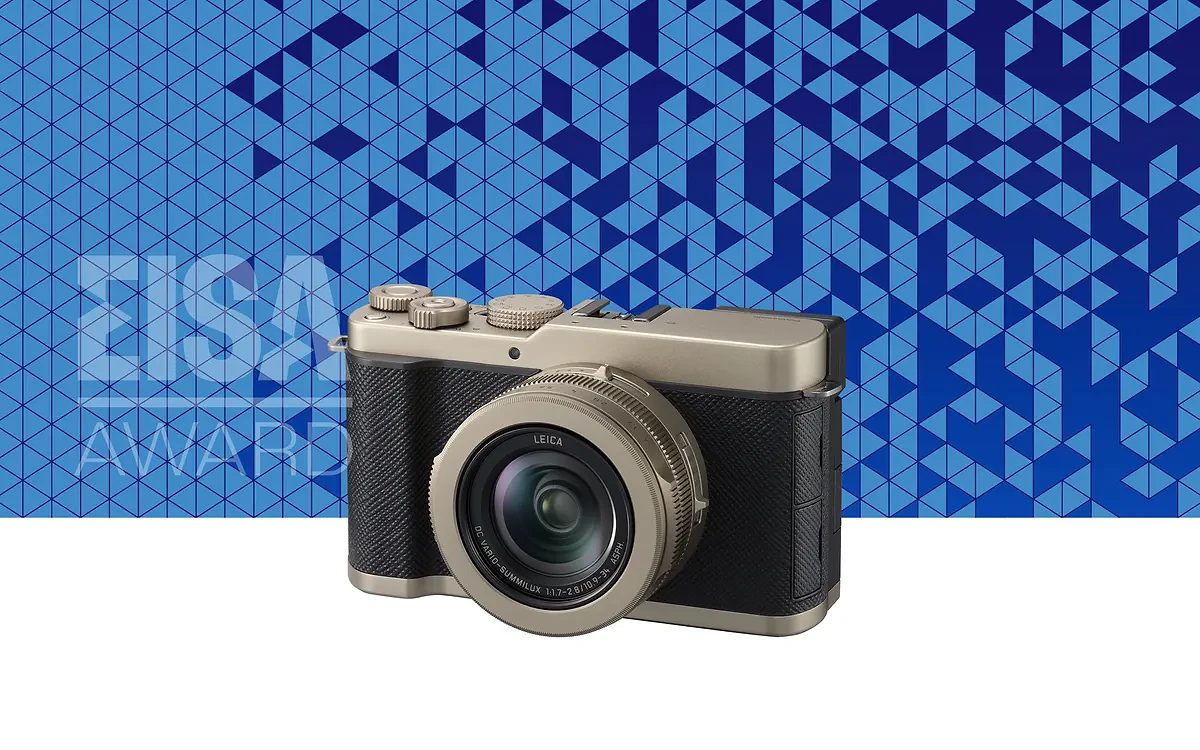 Compact Leica camera with metallic and black body in front of a blue geometric patterned background with "EISA Award" text