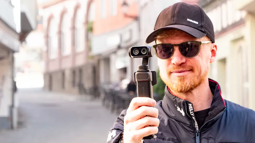 Man holding the Insta360 Luna Ultra vlogging camera on a sunny day in an old town
