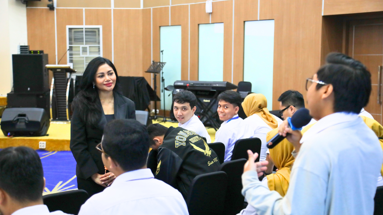 Presenter with microphone among seated students in a school hall
