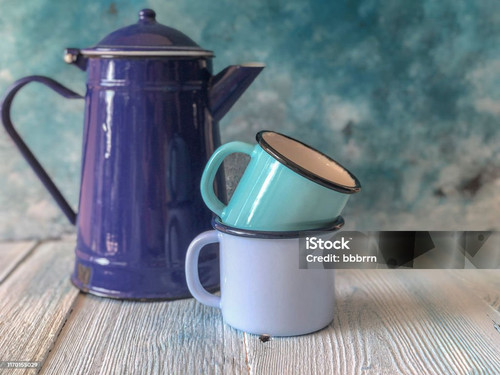 blue colored enamel teapot and retro mugs on a wooden table with copy space.jpg