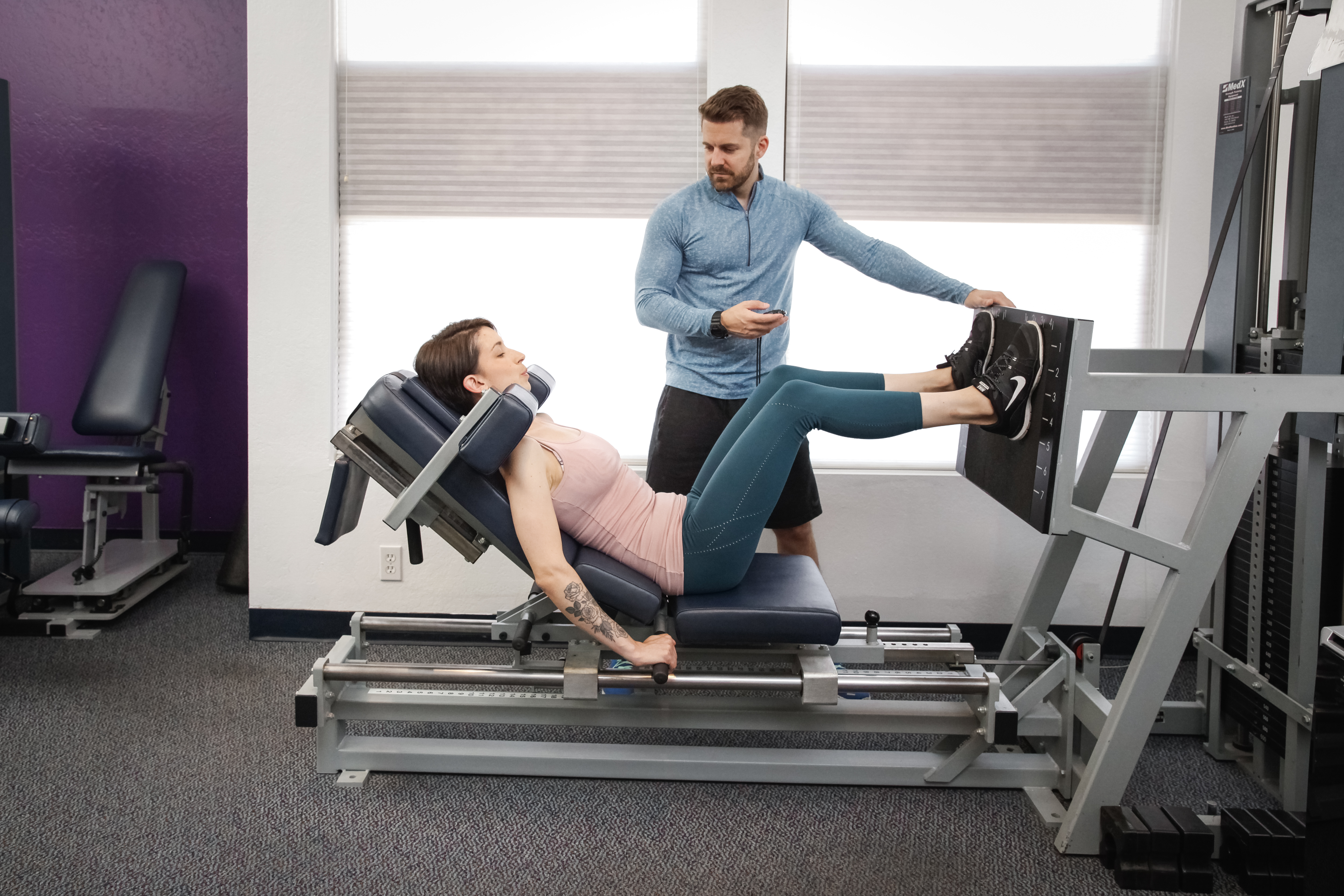 Strength Code trainer timing a client's leg press set inside the Toluca Lake studio