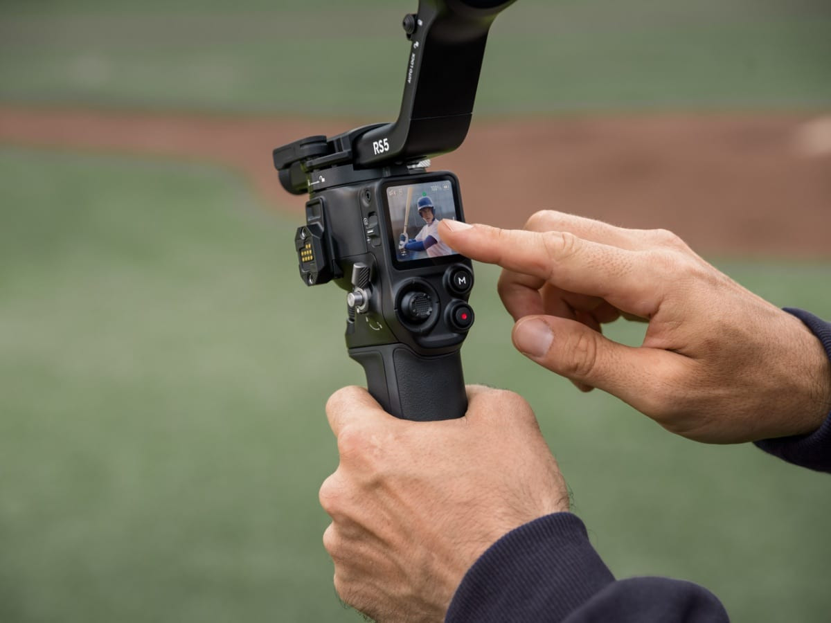 Ảnh chụp cận cảnh người dùng thao tác trên màn hình của gimbal RS 5 ngoài bối cảnh sân cỏ