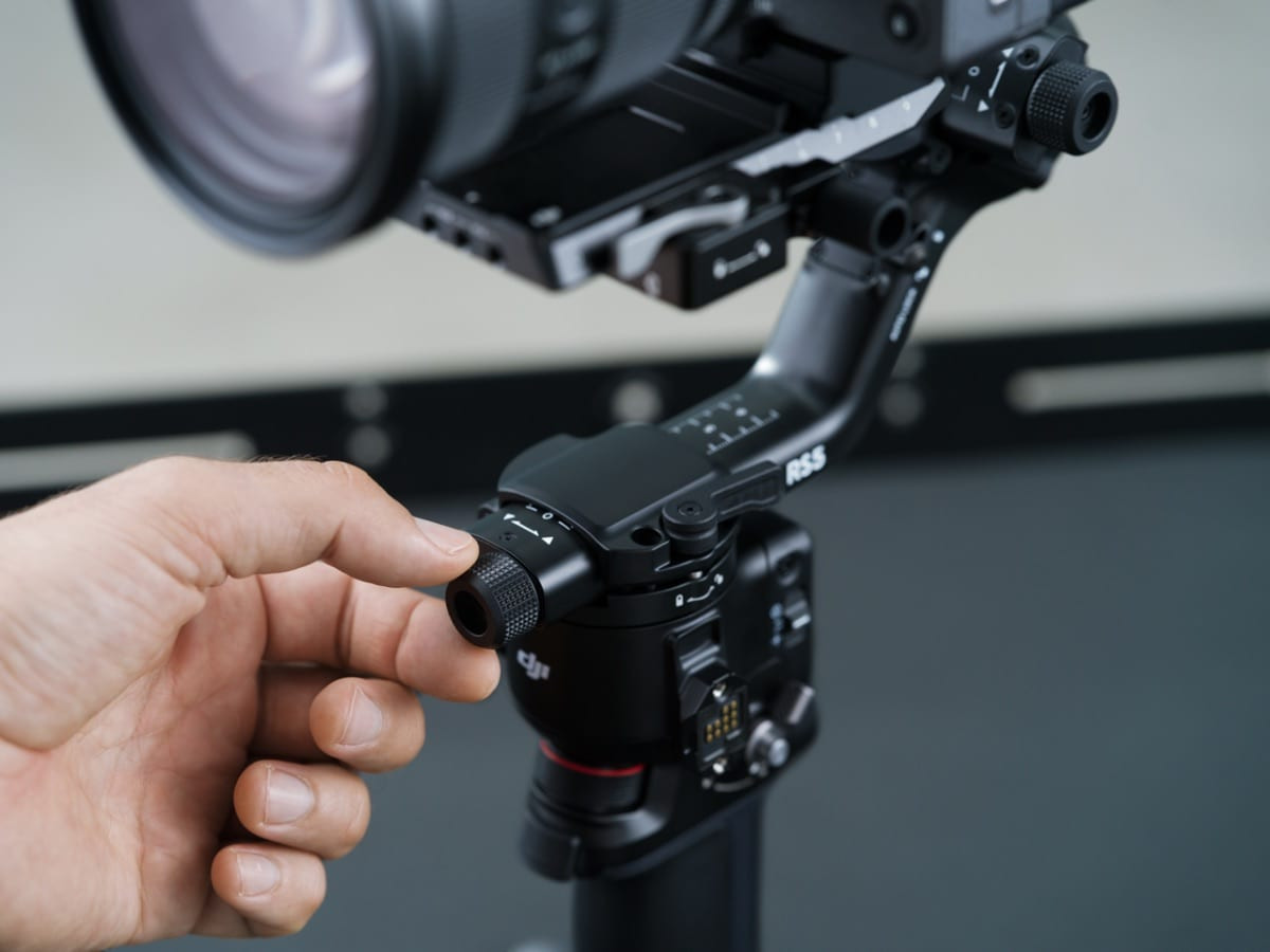 Ảnh chụp cận cảnh bàn tay thao tác với gimbal DJI RS 5 gắn trên thiết bị quay phim chuyên nghiệp