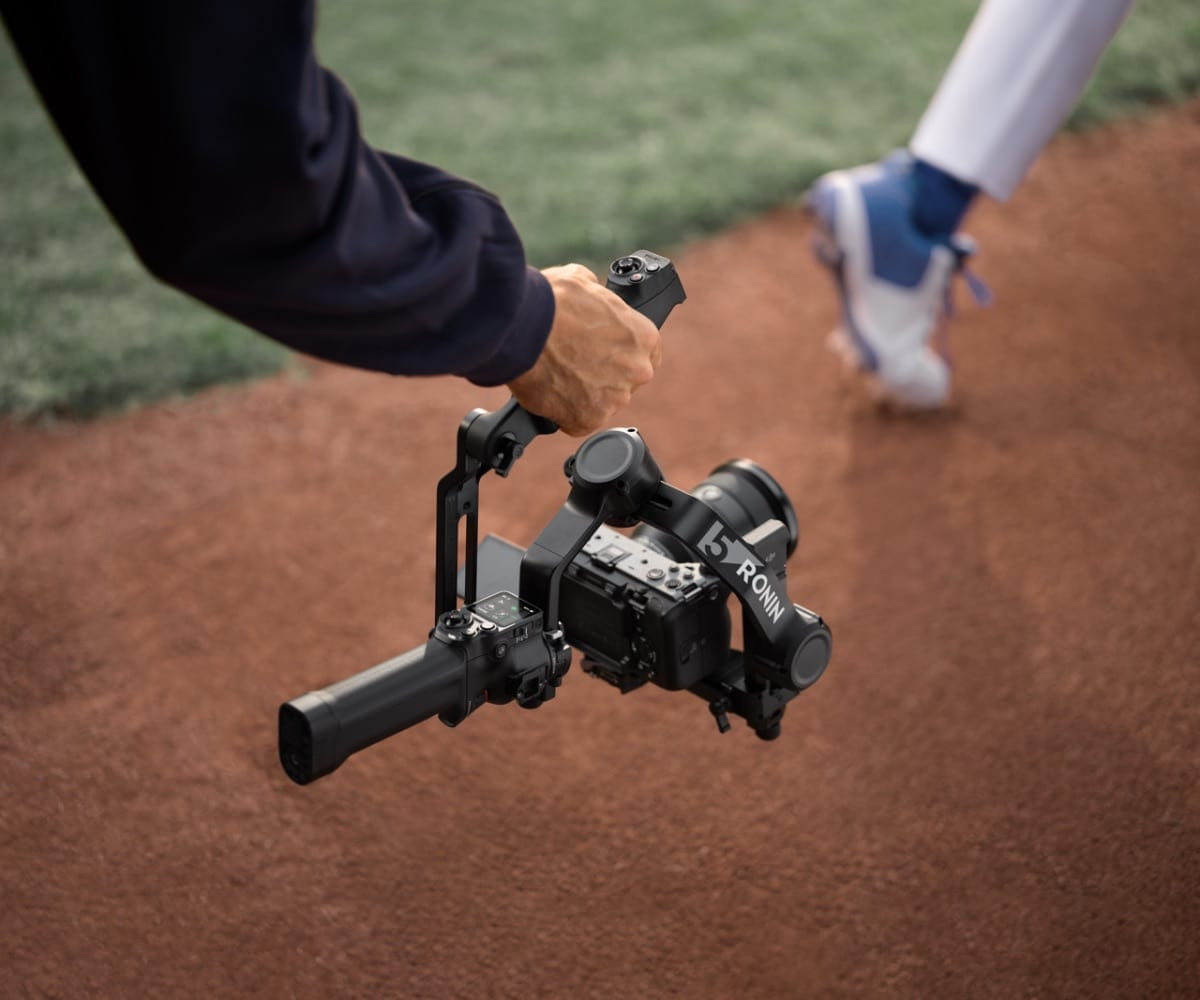 Cầm gimbal RS 5 của DJI trên nền sân đất đỏ ngoài trời