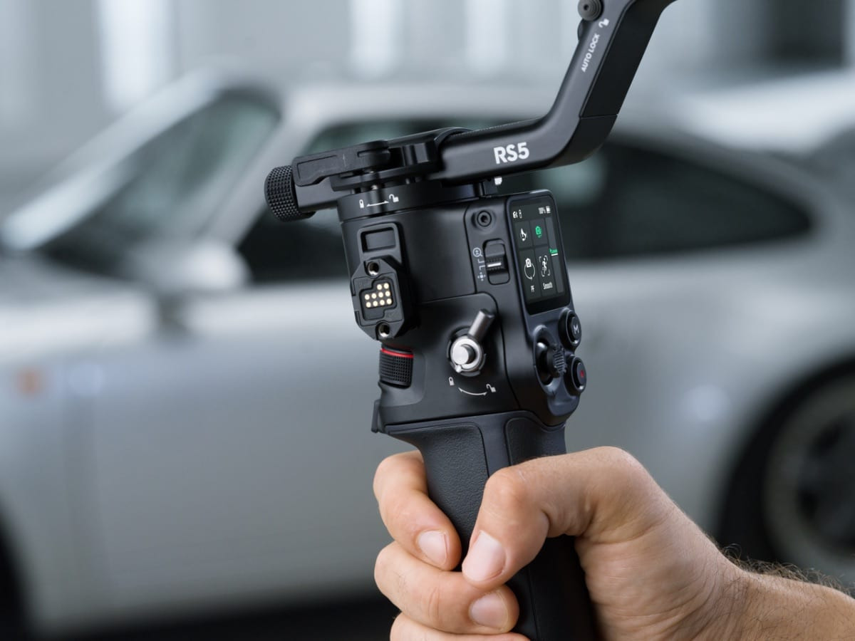 Cầm gimbal RS 5 chuyên nghiệp trước chiếc xe hơi trong bối cảnh ngoài trời
