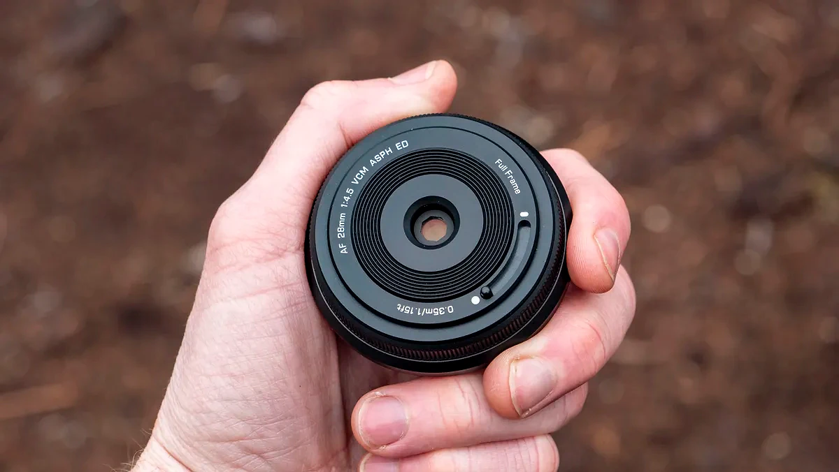 Viltrox AF 28mm f/4.5 body cap lens in photographer's hand