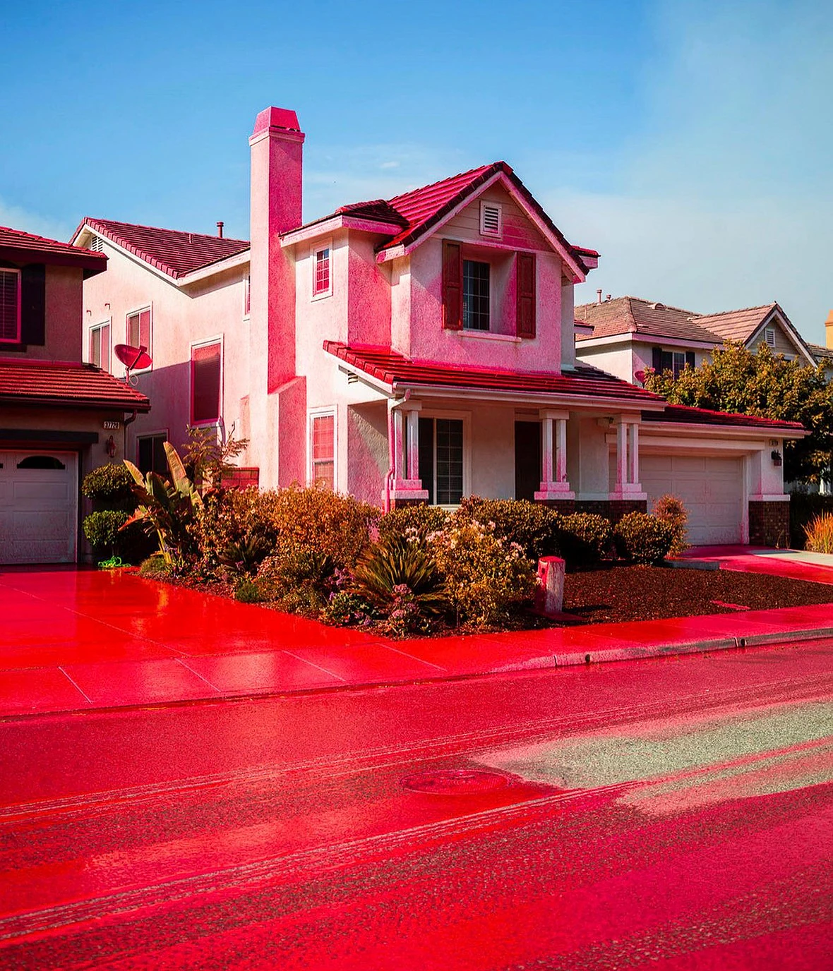 red fire retardant covers the road and houses in a suburban neighborhood