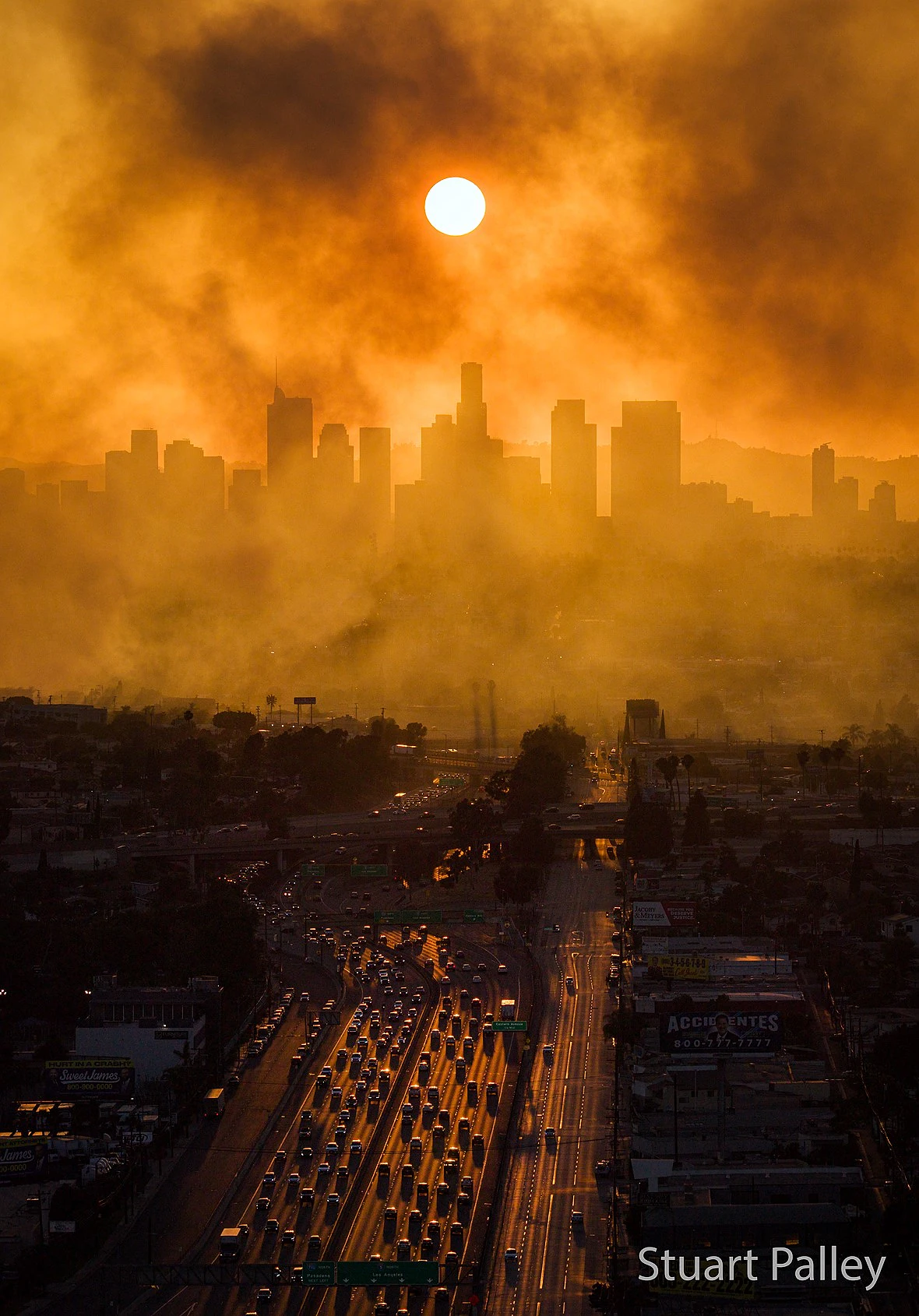 cars line a freeway that leads to a smoke covered cityscape