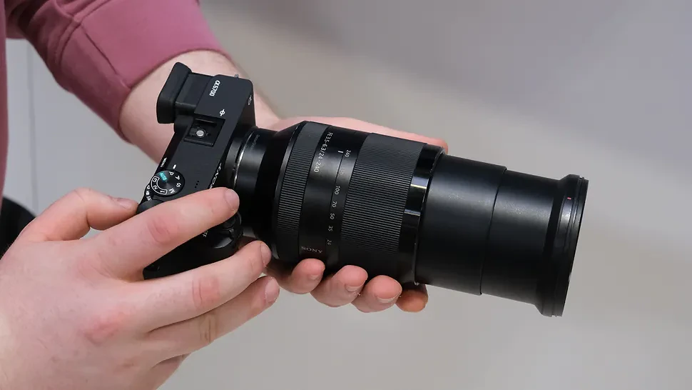 Sony FE 24-240mm lens attached to a Sony camera held in a pair of hands
