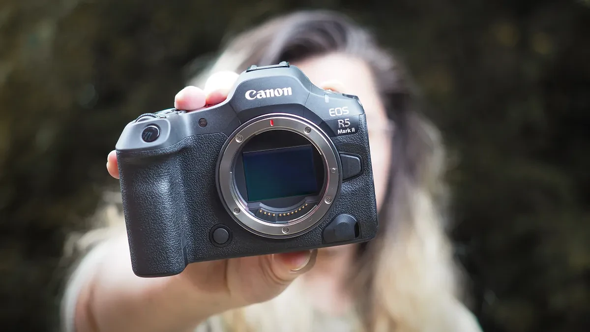 Canon EOS R5 Mark II being held out in front of a photographer's face, outdoors