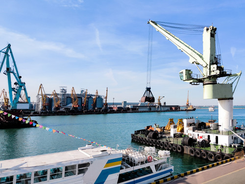 Floating cargo crane with a ladle in the seaport over the sea and Granary elevators, Tugboat assist,.jpg
