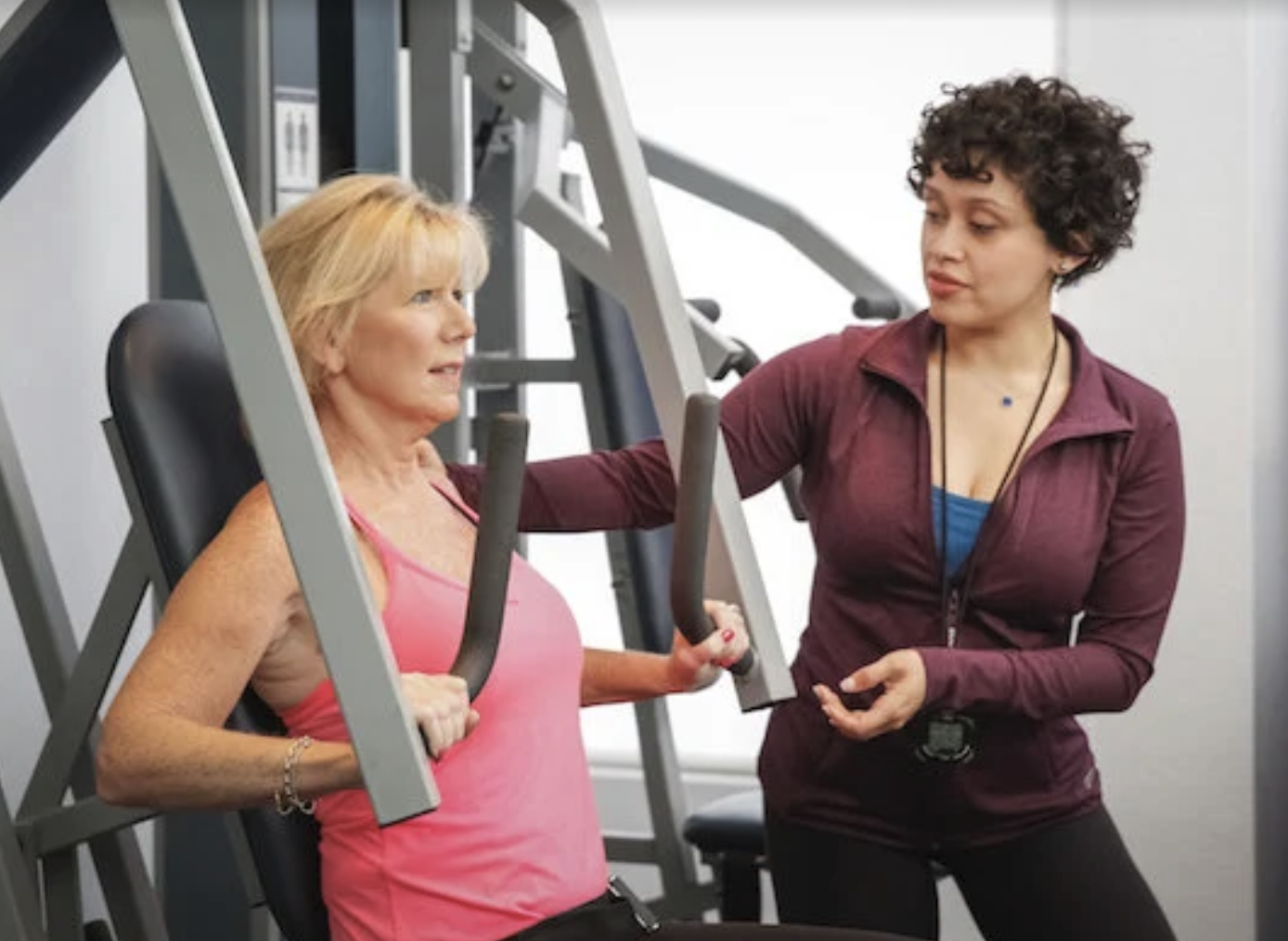Strength Code trainer coaching a client through a set on a supported chest press machine
