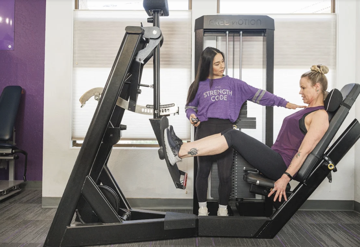 Strength Code trainer coaching a client through a repetition on the leg press