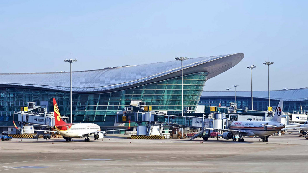 Hangzhou Xiaoshan airport apron view showing multiple commercial airplanes parked at gates with the curved terminal building behind