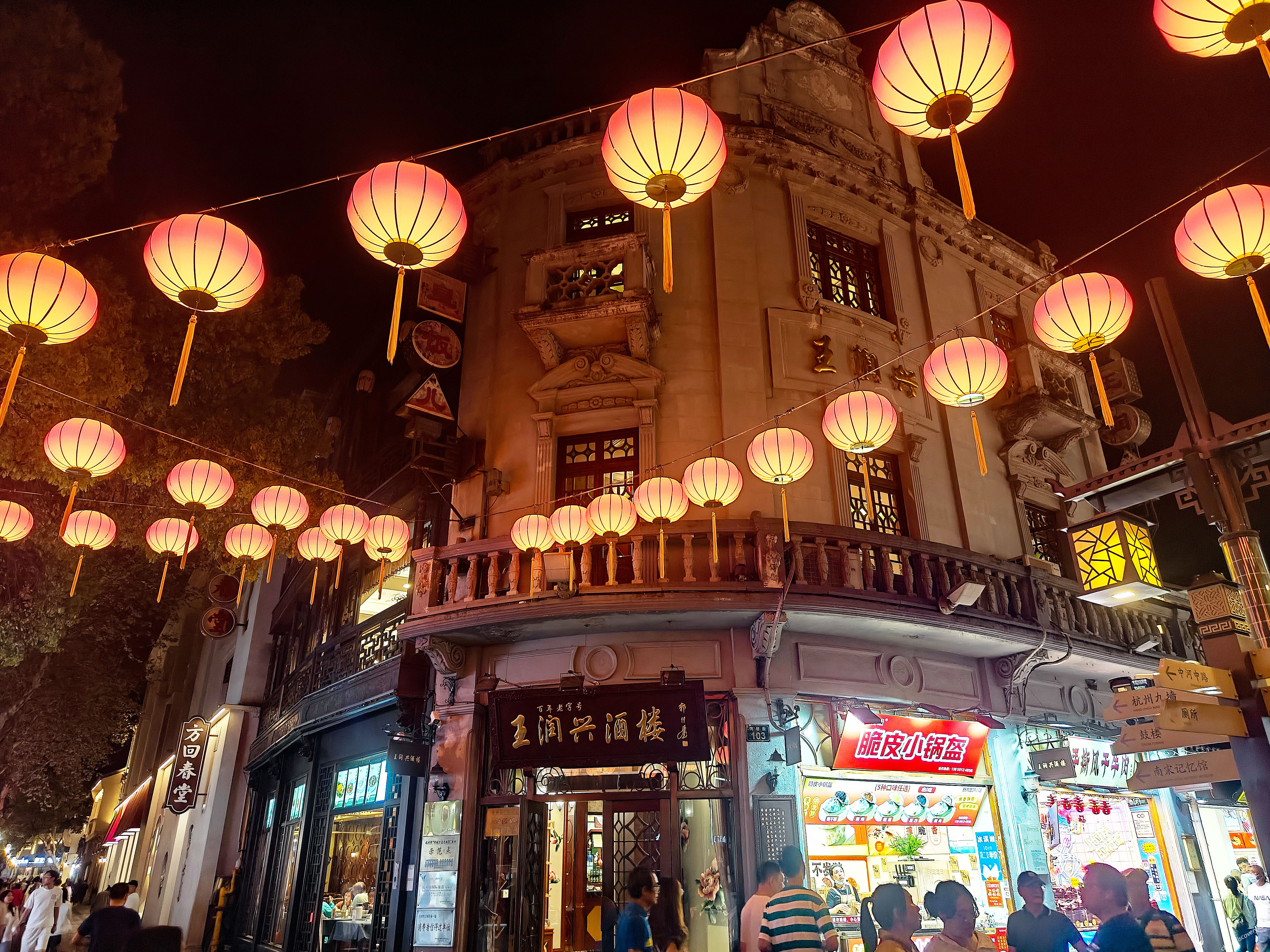 Hefang ancient street at night with red lanterns strung between traditional Chinese buildings and visitors walking