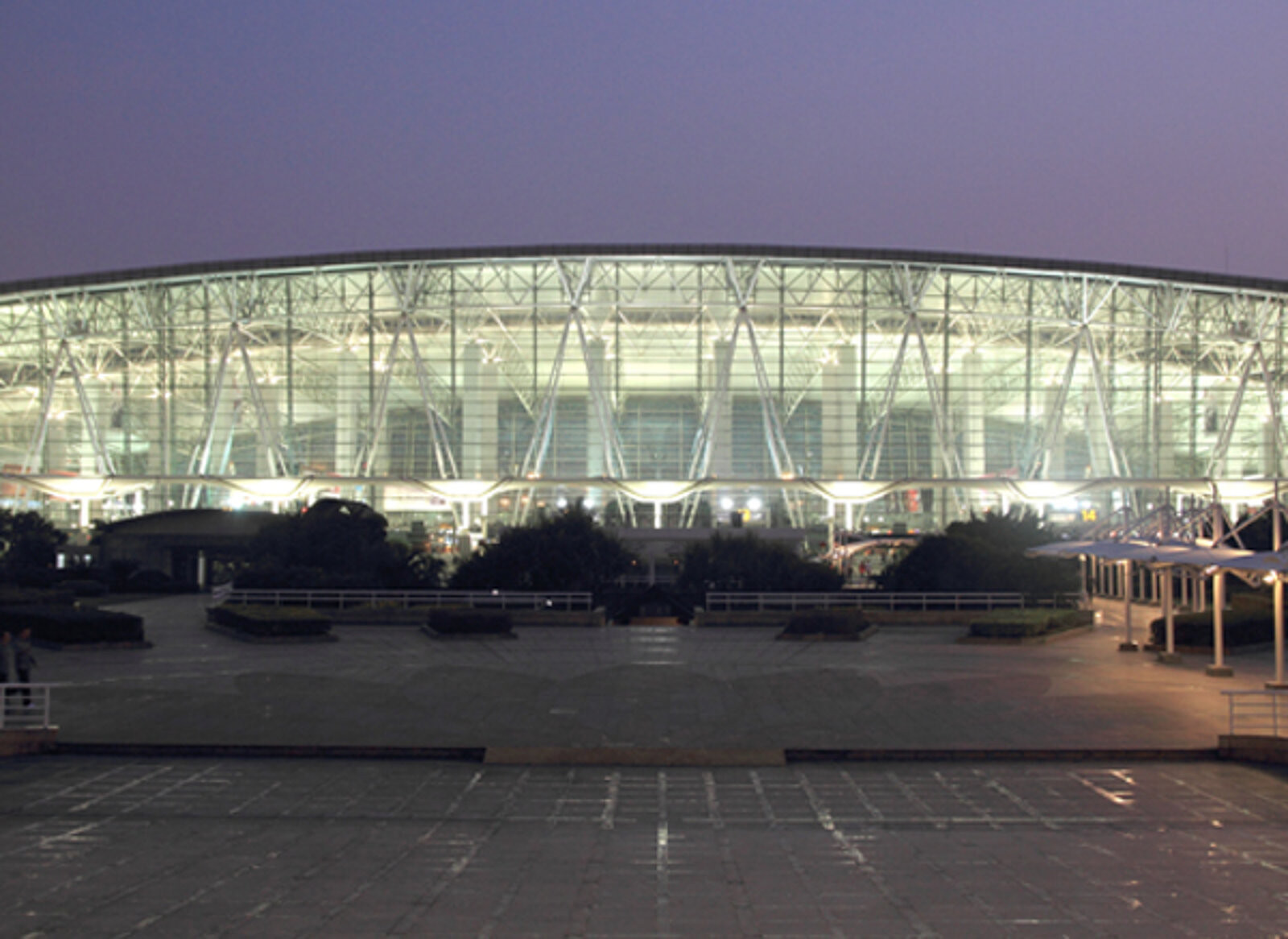 Hangzhou Xiaoshan International Airport terminal at night with curved steel-and-glass facade and lit interior
