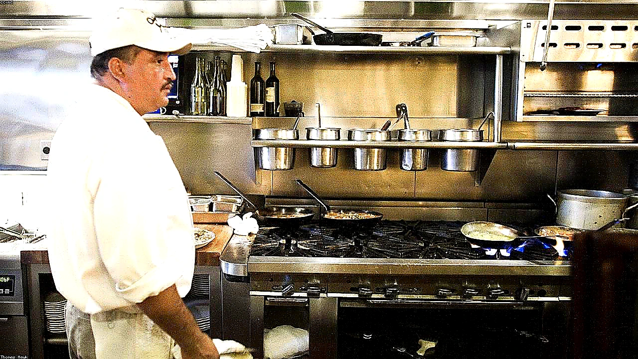 Vivid mid-article photo of chefs working under a well-lit CaptiveAire-style canopy hood